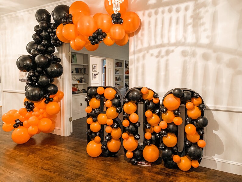 May include: A Halloween decoration made of black and orange balloons in the shape of the word "BOO".