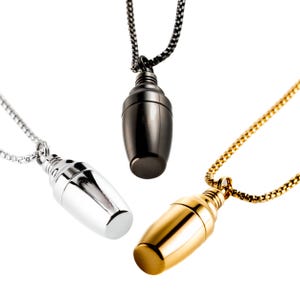 May include: Three pendant necklaces with a teardrop-shaped design. One is silver, one is black, and the other is gold. Each pendant hangs from a matching chain, creating a minimalist and elegant look.