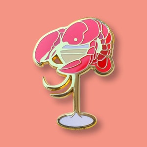 May include: Gold-tone lobster pin with red and pink enamel, holding a martini glass with a white and gold rim.