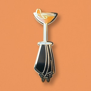 May include: Gold-colored enamel pin of a cocktail glass with a black bat-shaped base.