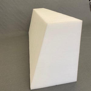 May include: White foam wedge pillow. The pillow is shaped like a triangle and is designed to elevate the head and shoulders.