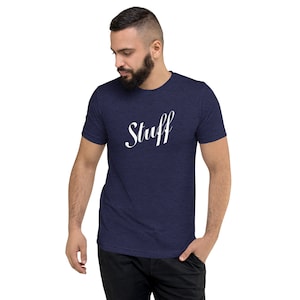Puede incluir: Una camiseta azul marino con la palabra "Stuff" impresa en letras blancas en cursiva.