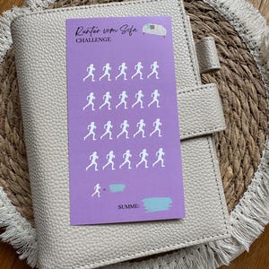 Könnte beinhalten: Eine lila Karte mit dem Text "Runter vom Sofa CHALLENGE" und einer weißen Silhouette eines Sofas. Auf der Karte befinden sich 20 weiße Silhouetten von laufenden Personen. Die Karte hat unten einen blauen Bereich mit der Aufschrift "SUMME:"