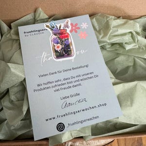 Könnte beinhalten: Eine Dankeskarte mit einer floralen Illustration eines Glases mit Blumen. Die Karte hat den Text "fruehlingserwachen.shop" und "_fruehlingserwachen" aufgedruckt. Die Karte hat auch den Text "Vielen Dank für Deine Bestellung! Wir hoffen sehr, dass Du mit unseren Produkten zufrieden bist und wünschen Dir viel Freude damit. Liebe Grüße Laudia" aufgedruckt.