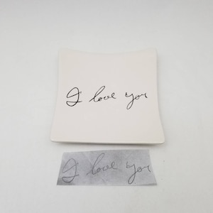 May include: White ceramic dish with a curved edge. The dish has the words "I love you" written in black cursive.