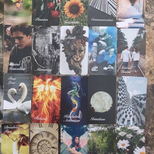May include: A selection of tarot cards with diverse imagery and text. Cards display a butterfly, flowers, a sunflower, and abstract patterns. Other cards depict a mask, a couple, swans, and a phoenix. The cards are labelled with terms such as "Nature," "Passion," and "Divine Masculine."