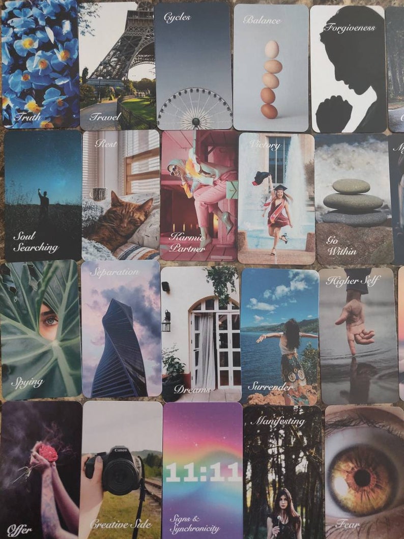 May include: A selection of tarot cards with diverse imagery and text. The cards display illustrations of a Ferris wheel, the Eiffel Tower, a cat, a woman, and other symbolic images. Text includes words such as "Truth", "Travel", "Cycles", and "11:11".