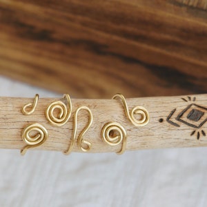 Könnte beinhalten: Ein Holzstab mit einem eingebrannten geometrischen Muster auf der Oberfläche. Der Stab ist mit mehreren goldenen Drahtringen verziert.