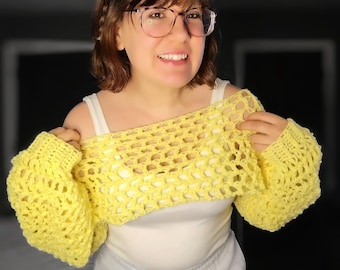 May include: A yellow crocheted off-the-shoulder top with a loose, open-weave design. The top has long sleeves and a cropped length.