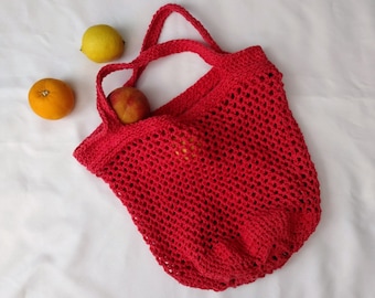 May include: Red crocheted mesh bag with two pieces of fruit inside. The bag has a long handle and is made of a soft, flexible material.