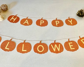 May include: A two-line banner featuring glittery orange pumpkin-shaped cutouts strung on white twine. Each pumpkin displays a single cream-coloured letter spelling out HAPPY HALLOWEEN. The banner is accented by small decorative pinecones and pumpkins.