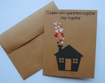 May include: A brown card with the text "Couples who quarantine together stay together" and a black silhouette of a house with hearts coming out of the chimney.