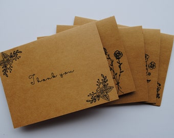 May include: Set of five brown kraft paper thank you cards with black floral designs and the text "Thank you".