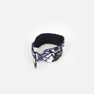 Puede incluir: Una correa estampada en negro, morado y blanco, con un interior de malla negra y un mosquet&oacute;n negro. La palabra "hosh" est&aacute; impresa en la correa.