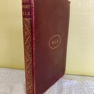 May include: A burgundy leather-bound book with gold lettering on the spine that reads "The Pocket R.L.S."