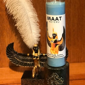Op de afbeelding: Een blauwe kaars met een gouden label waarop de Egyptische godin Maat is afgebeeld. Het label vermeldt "Maat Neteru Divine Truth, Justice, Order & Righteousness".