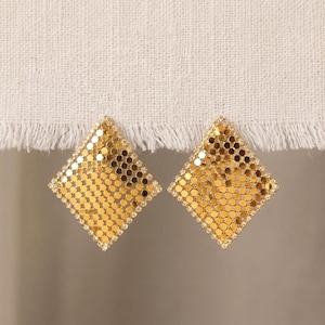 Könnte beinhalten: Ein Paar rautenförmige Ohrringe aus einem flexiblen, goldfarbenen Metallgeflecht. Jeder Ohrring besteht aus einem Gitter aus kleinen, kreisförmigen, reflektierenden goldenen Scheiben, die von einem dünnen Metallrahmen eingefasst sind.