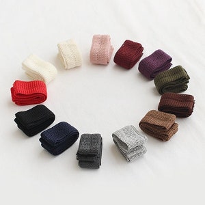 May include: Assortment of 15 different colours of knit elastic trim. The trim is folded and stacked in a circle on a white background.