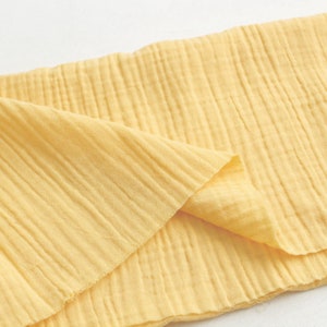 May include: A yellow fabric with a crinkled texture. The fabric is folded in half and the edges are visible.