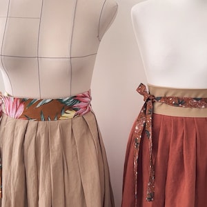 Pode incluir: Duas saias com diferentes cintos de tecido com padr&atilde;o floral. A saia &agrave; esquerda &eacute; de cor castanho claro e a saia &agrave; direita &eacute; de cor ferrugem.