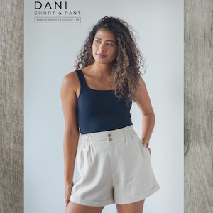 May include: A woman in a navy vest top and beige shorts. The shorts are high-waisted with two buttons. The image includes text: "DANI SHORT & PANT sewing pattern sizes 0-18" and "TRUE BIAS".