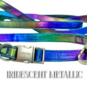 Może przedstawiać: Iridescentny metaliczny zestaw obroży i smyczy dla zwierząt. Obroża posiada srebrną klamrę z logo "SurferCat". Zestaw przechodzi przez odcienie niebieskiego, zielonego i fioletowego. Tekst "IRIDESCENT METALLIC" jest wyświetlany na dole.