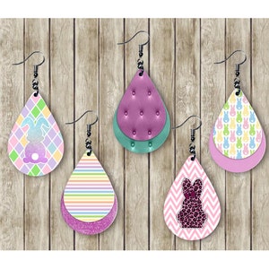 May include: Five pairs of teardrop earrings with various Easter-themed designs. The earrings feature patterns like pastel diamonds, stripes, bunny silhouettes, and a pink and black leopard print bunny. Each earring has a silver hook.