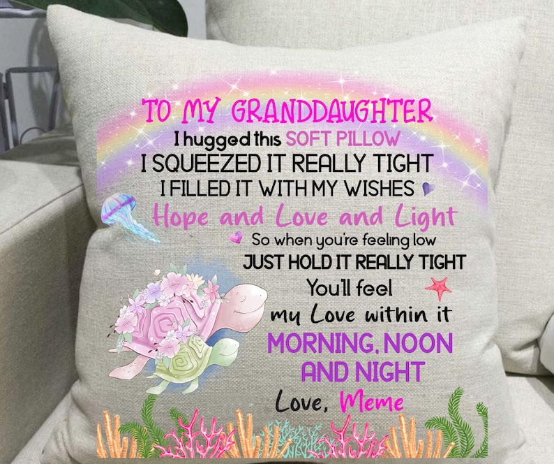 May include: A square, off-white pillow with a printed design. The design includes a rainbow, a jellyfish, and a turtle with flowers. Text reads "TO MY GRANDDAUGHTER" and a loving message from "Meme."