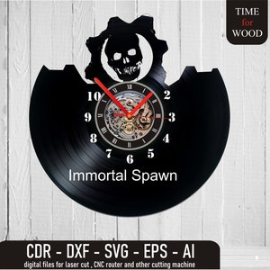 Puede incluir: Reloj de vinilo negro con un diseño de calavera y engranaje. La esfera del reloj tiene números romanos y las palabras "Immortal Spawn".