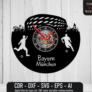 Puede incluir: Reloj de vinilo negro con una silueta de un jugador de fútbol, una portería de fútbol y aficionados. La esfera del reloj presenta un mecanismo de reloj con números romanos y el texto "Bayern München".