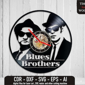 May include: Black and white vinyl record clock featuring the Blues Brothers. The clock face is a black vinyl record with a clock mechanism in the center. The Blues Brothers are depicted in black silhouettes with the text "Blues Brothers" below them.