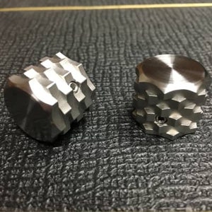 May include: Two silver metal knobs with a geometric design. One knob has a smooth, polished finish, while the other has a textured, ridged finish.