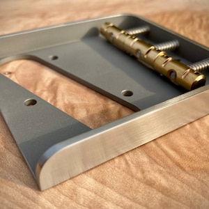 以下が含まれることがあります： 真鍮のサドルと取り付けネジが付いた銀色のギターブリッジ。ブリッジは6弦ギター用に設計されています。