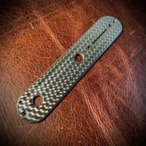 May include: A silver guitar pickguard with a textured surface and two holes for mounting screws.