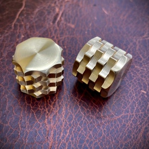 May include: Two gold-colored metal fidget toys. One is a hexagonal shape with multiple layers, the other is a cube with a textured surface.