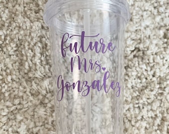 May include: Clear plastic tumbler with a purple inscription that reads "future Mrs. Gonzalez" with a small heart symbol.