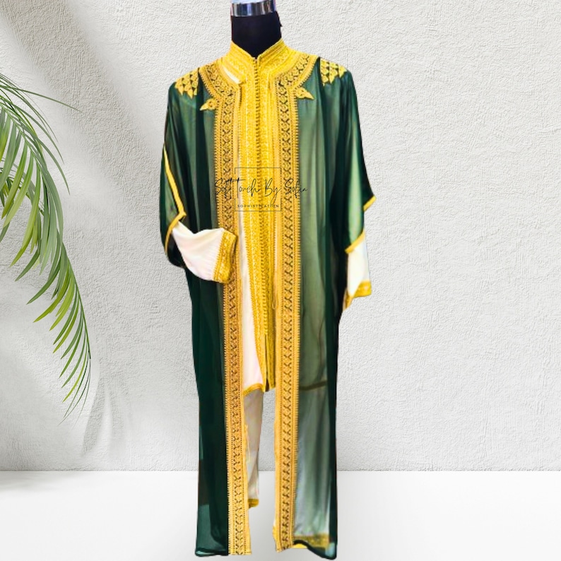 May include: A green and gold embroidered robe with white accents. The robe features intricate gold embroidery along the collar, cuffs, and front panels. The sleeves are wide and flowing, and the robe is displayed on a mannequin.