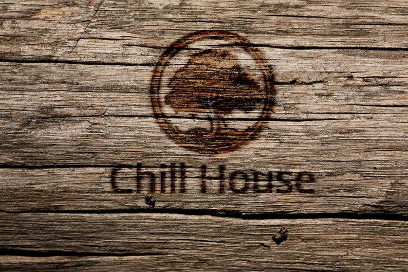 Op de afbeelding: Een rustiek houten bord met een ingebrand beeld van een boom en de tekst "Chill House".