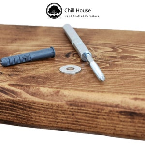 K&ouml;nnte beinhalten: Nahaufnahme einer Holzregal mit einer silbernen Schraube, einem grauen Kunststoffd&uuml;bel und einer silbernen Unterlegscheibe. Das Regal wird von Chill House, Hand Crafted Furniture, hergestellt.