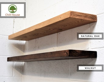May include: Two wooden shelves mounted on a white brick wall. The top shelf is natural oak and the bottom shelf is walnut.