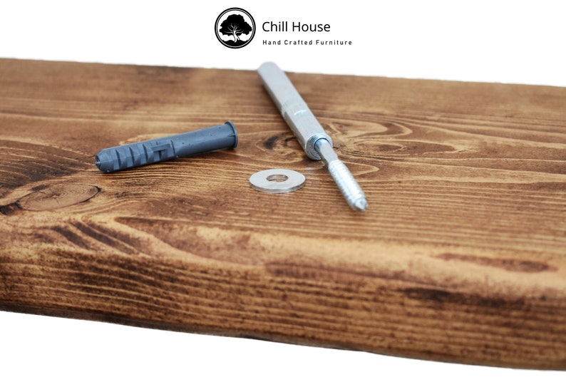 Op de afbeelding: Close-up van een houten plank met een zilveren schroef, een grijze plastic plug en een zilveren ring. De plank is gemaakt door Chill House, Hand Crafted Furniture.