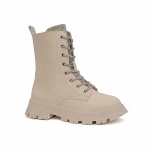 May include: Cream-colored combat boot with a chunky lug sole. The boot features a lace-up design with silver-toned laces and a decorative band of rhinestones at the top. The boot is made of a smooth material and has a pull tab at the back.