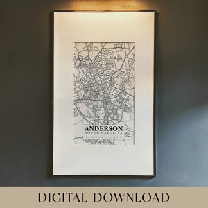 May include: A framed black and white map print of Anderson, South Carolina with the city's name and coordinates printed below the map.