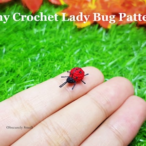May include: A tiny crocheted ladybug with black legs and red and black spots. The ladybug is sitting on a finger.