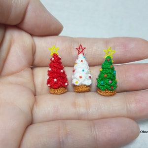 May include: Three miniature crocheted Christmas trees, one red, one white, and one green, with colorful beads and star toppers.