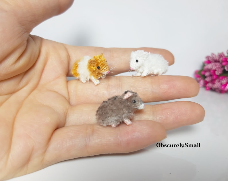 May include: Three small crocheted hamster figurines. One is brown, one is white, and one is orange and white.