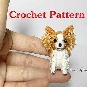 May include: A crocheted dog figurine with a white body and brown and white head. The text "Crochet Pattern" is displayed in red. The figurine is held in a hand.