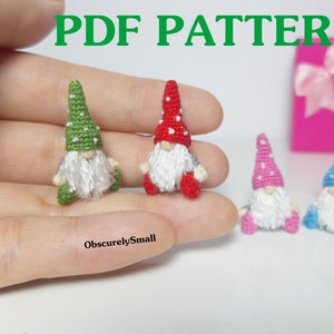 May include: Four crocheted gnomes, each with a different colored hat: green, red, pink, and blue. The gnomes are sitting on a hand, with the text "ObscurelySmall" below them.