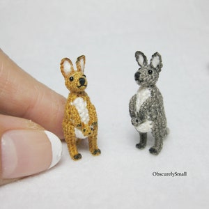 May include: Two crocheted kangaroo figurines, one brown and one gray, each holding a smaller crocheted kangaroo joey in their pouch.