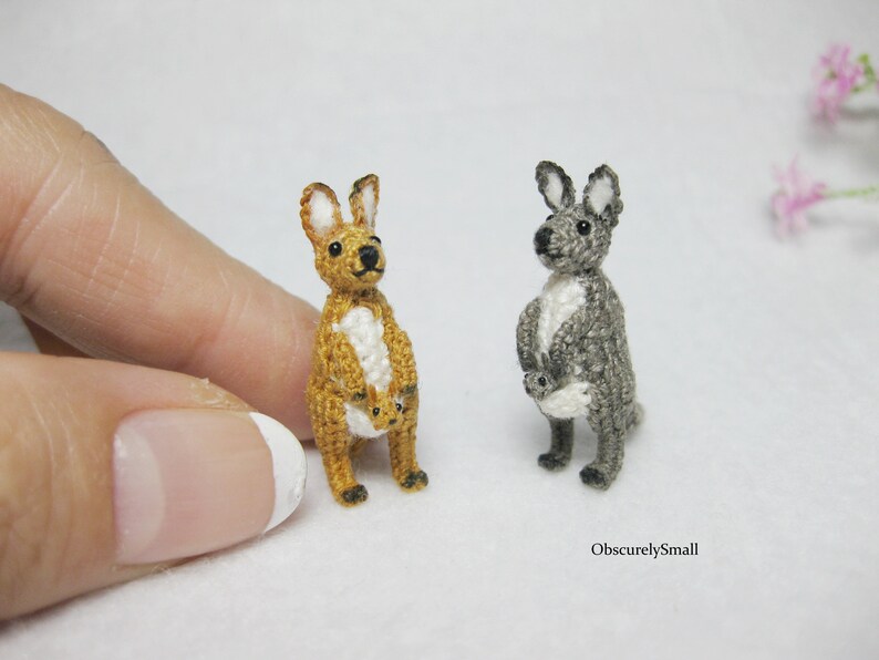 May include: Two crocheted kangaroo figurines, one brown and one gray, each holding a smaller crocheted kangaroo joey in their pouch.